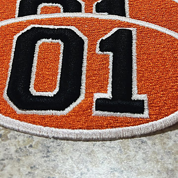 An orange patch with the number 01 in raised black embroidery