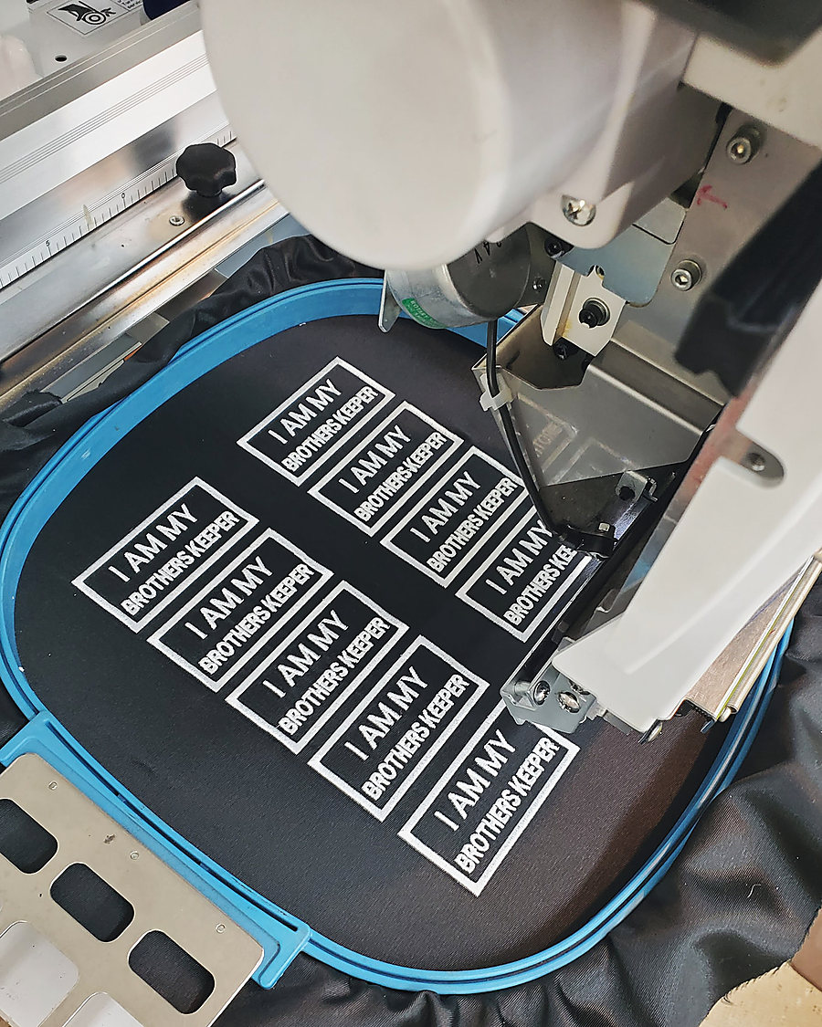 A sheet of I Am My Brothers Keeper patches being stitched on the embroidery machine