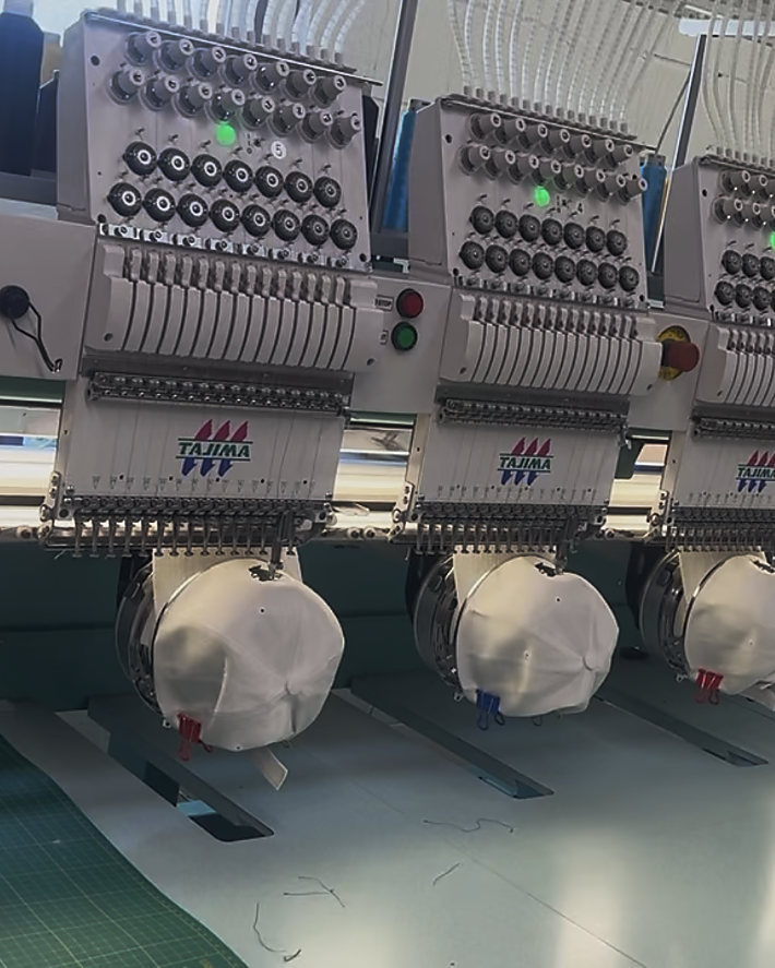 Six white caps being stitched at once on a six-head embroidery machine