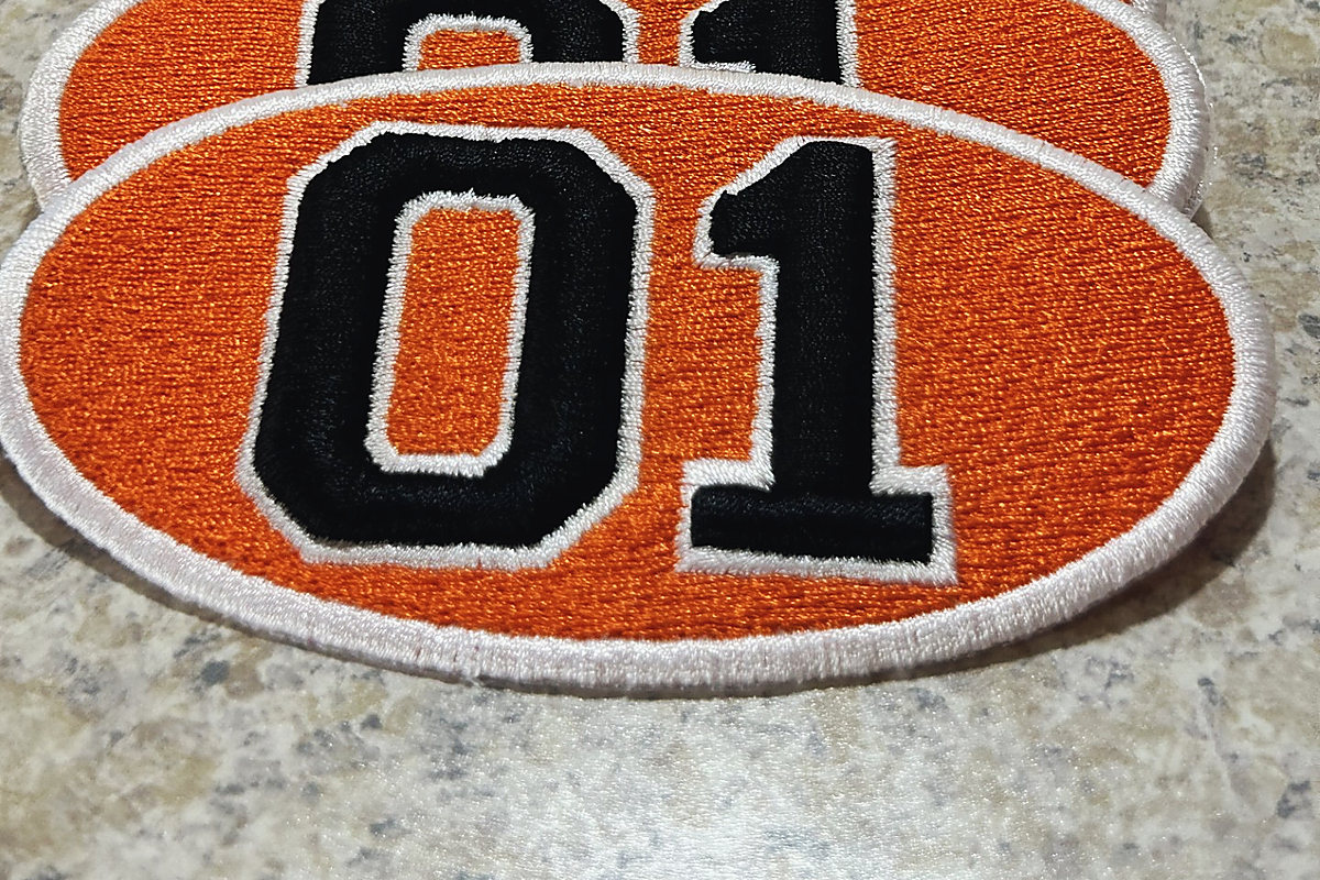 Orange oval patches with the number 01 raised in black 3D embroidery